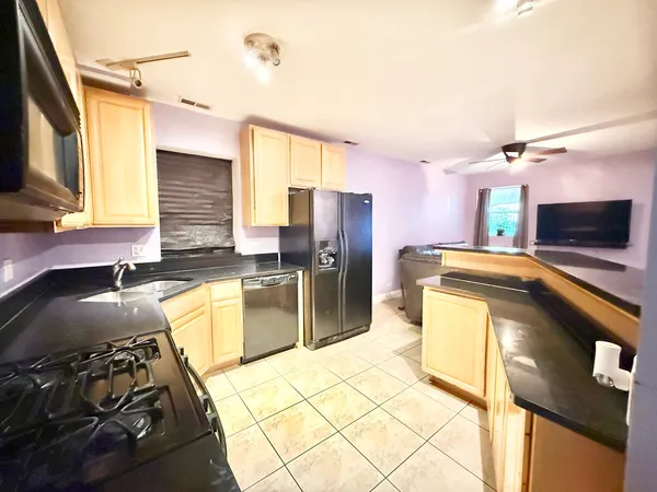a kitchen with granite countertop a refrigerator and a stove top oven