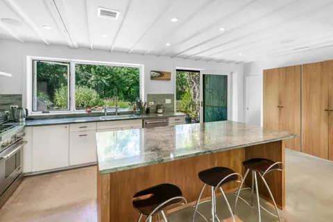 a kitchen with stainless steel appliances granite countertop a stove a sink and a granite counter tops with white cabinets next to a window
