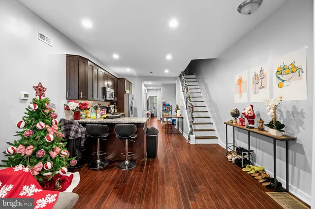 a kitchen with stainless steel appliances granite countertop a refrigerator dining table and chairs with wooden floor