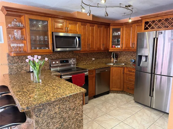 a kitchen with stainless steel appliances granite countertop a refrigerator a stove a sink and a microwave