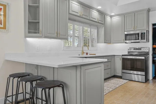 a kitchen with stainless steel appliances granite countertop a kitchen island a stove a sink and a microwave