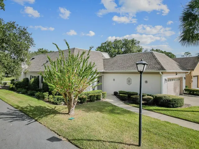 a view of a house with a small yard plants and a large tree