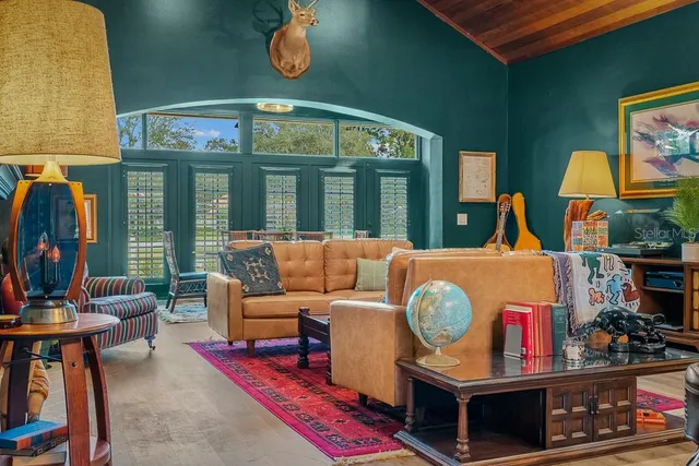 a living room with furniture a floor to ceiling window and a flat screen tv