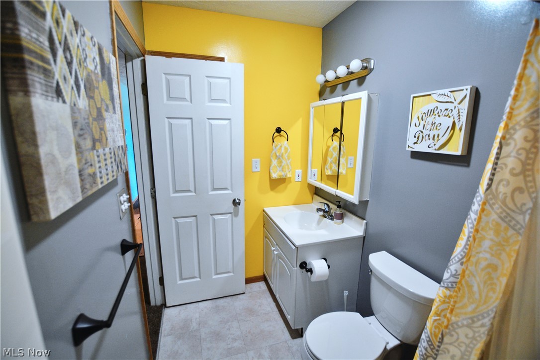 7956 Sidley Road Thompson, OH 44086 - Photo 18 of 25 Bathroom featuring vanity with extensive cabinet space, toilet, and tile floors