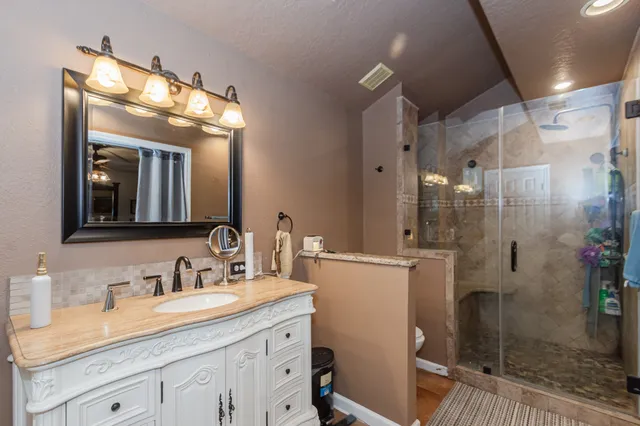 a bathroom with a granite countertop sink mirror and shower