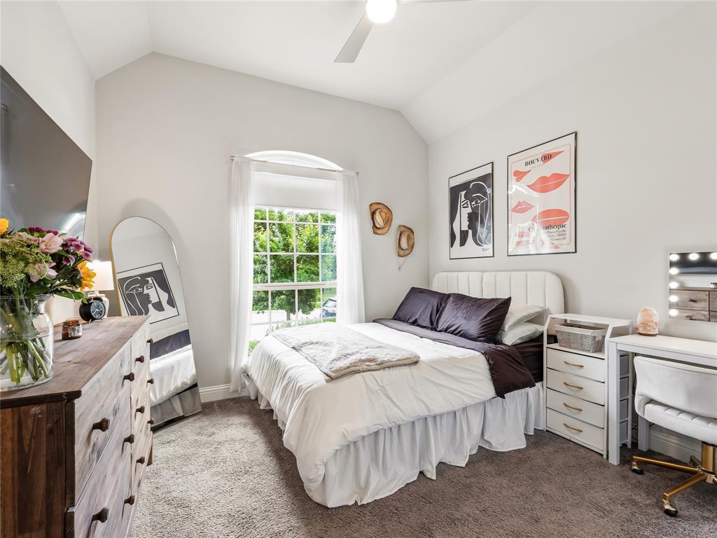 15340 Crape Myrtle Road Frisco, TX 75035 - Photo 26 of 40 Vaulted ceiling bedroom featuring a large arched window with grid details, soft carpet flooring, and a ceiling fan