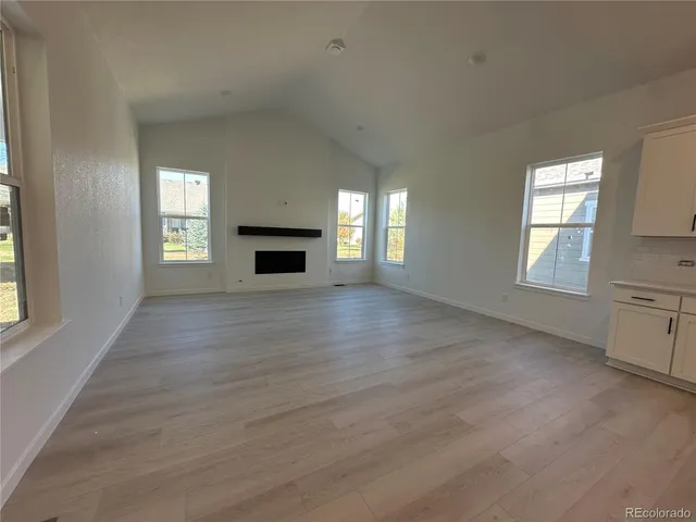 an empty room with wooden floor fireplace and windows