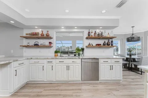 a kitchen with white cabinets stainless steel appliances and wooden floor
