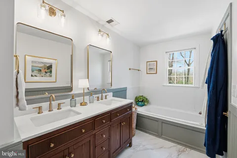 a bathroom with a double vanity sink a large mirror a bathtub and vanity