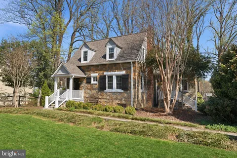 a view of a white house with a small yard and front a large tree