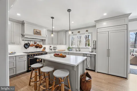 a kitchen with stainless steel appliances granite countertop a stove a sink dishwasher a refrigerator and white cabinets with wooden floor