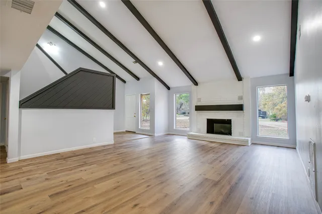 a view of an empty room with wooden floor fireplace and a window