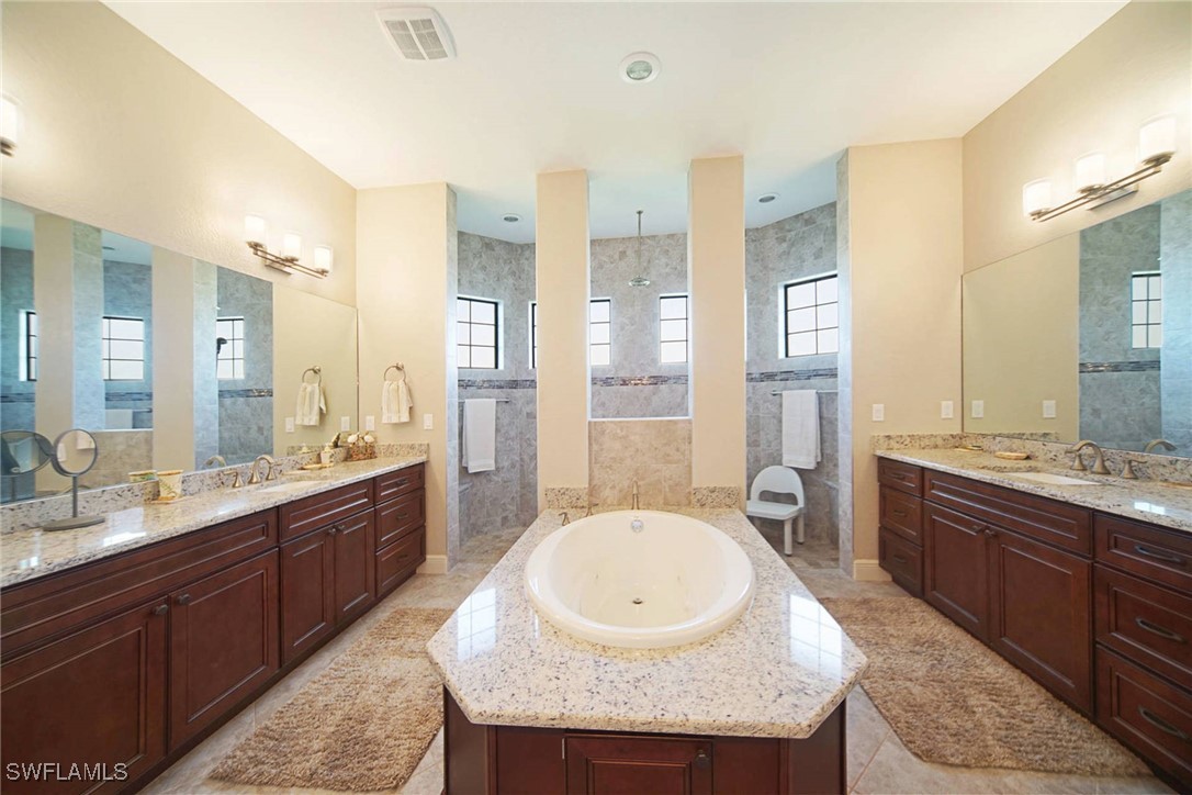 1502 Southwest 38th Street Cape Coral, FL 33914 - Photo 13 of 17 a large bathroom with a granite countertop double vanity sink a mirror and a bathtub