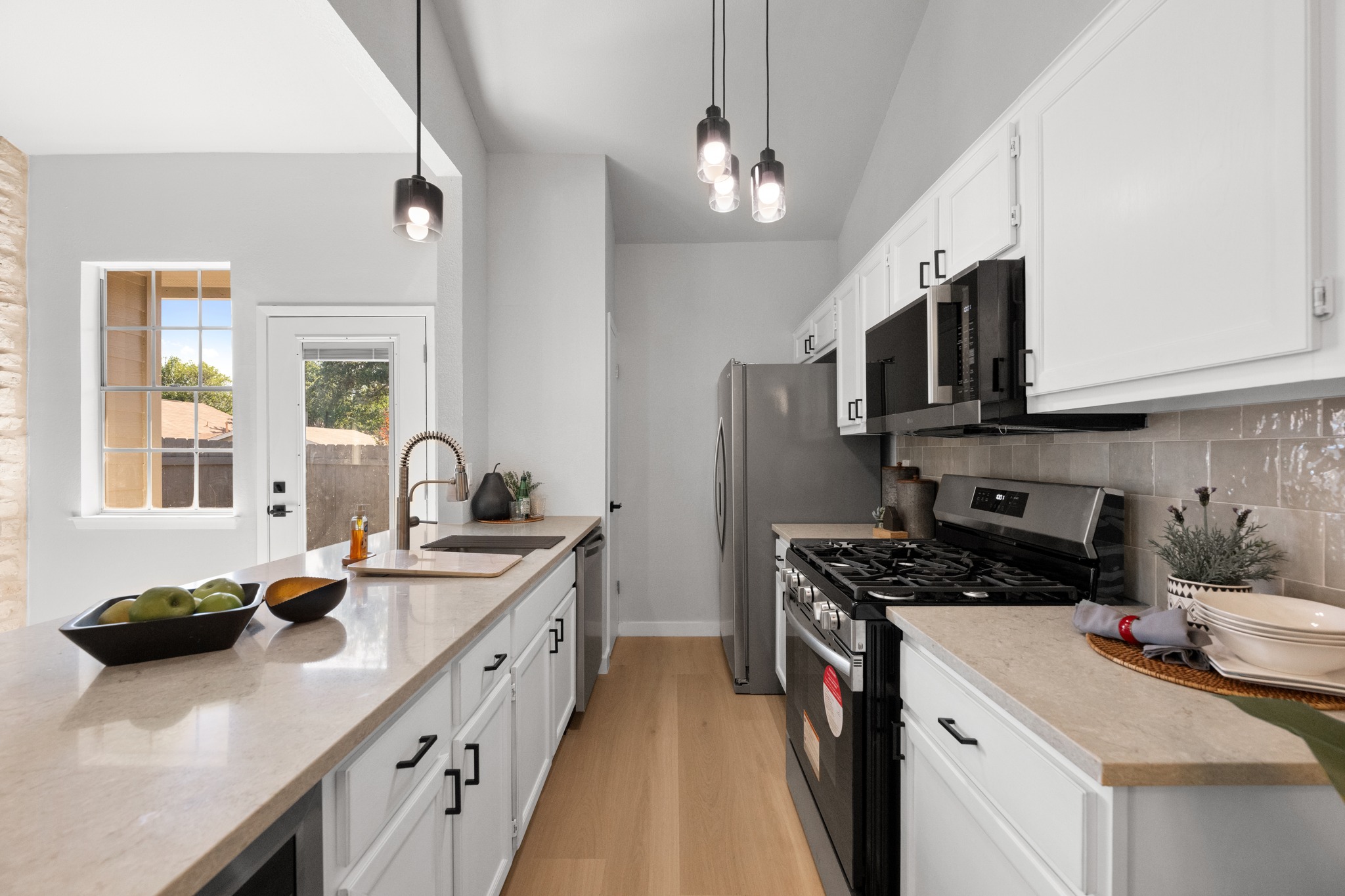 6501 Brush Country Road, Unit 120 Austin, TX 78749 - Photo 8 of 26 Open-concept kitchen and living area featuring light wood-finish flooring, modern lighting fixtures and a gorgeous light ash ceramic tile