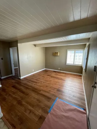 a view of empty room with window and wooden floor