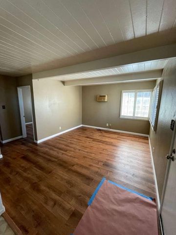 a view of empty room with window and wooden floor