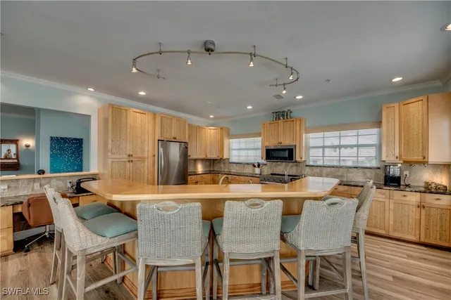 a kitchen with stainless steel appliances kitchen island granite countertop a dining table chairs and sink