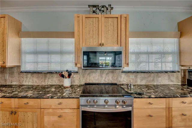 a kitchen with granite countertop a stove a sink and white cabinets