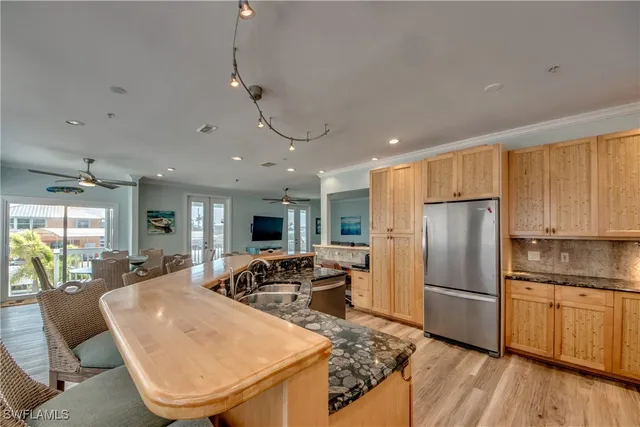 a kitchen with stainless steel appliances granite countertop a refrigerator a oven a sink a dining table and chairs with wooden floor