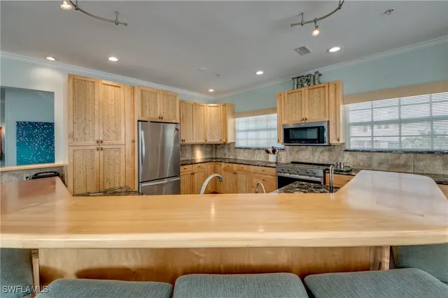 a large kitchen with stainless steel appliances kitchen island granite countertop a refrigerator a stove a sink dishwasher and white cabinets with wooden floor