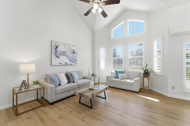 a living room with couches and a dining table with wooden floor
