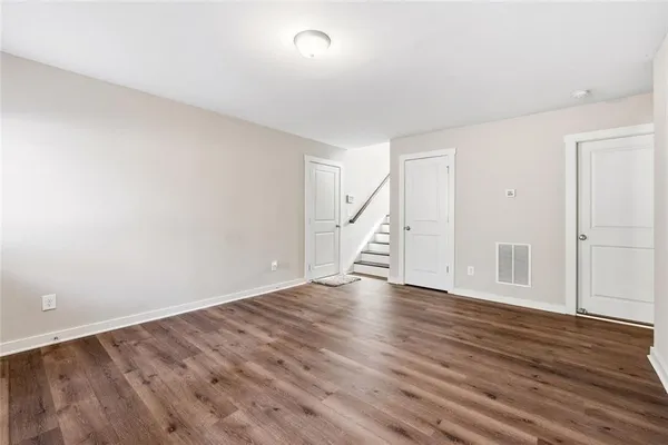 a view of an empty room with wooden floor and stairs