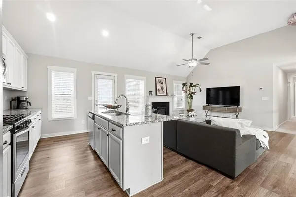 a kitchen with stainless steel appliances granite countertop a stove top oven a sink dishwasher and a oven with wooden cabinets