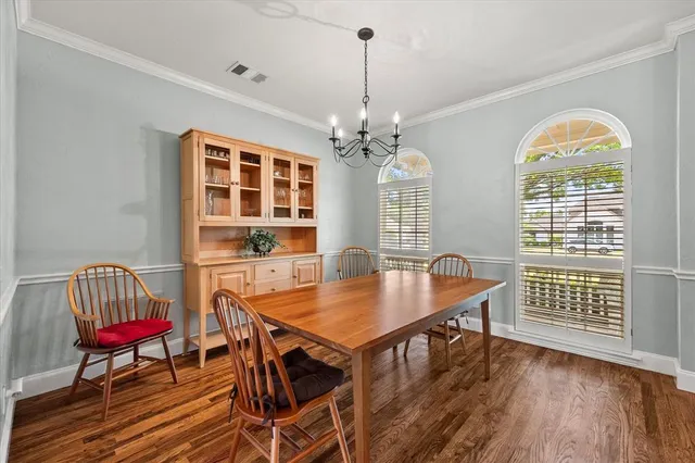 a dining room with wooden floor a chandelier a wooden table and chairs