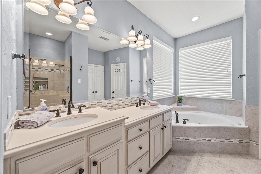 425 Chippendale Drive Heath, TX 75032 - Photo 18 of 37 a bathroom with a double vanity sink a large mirror and a bathtub