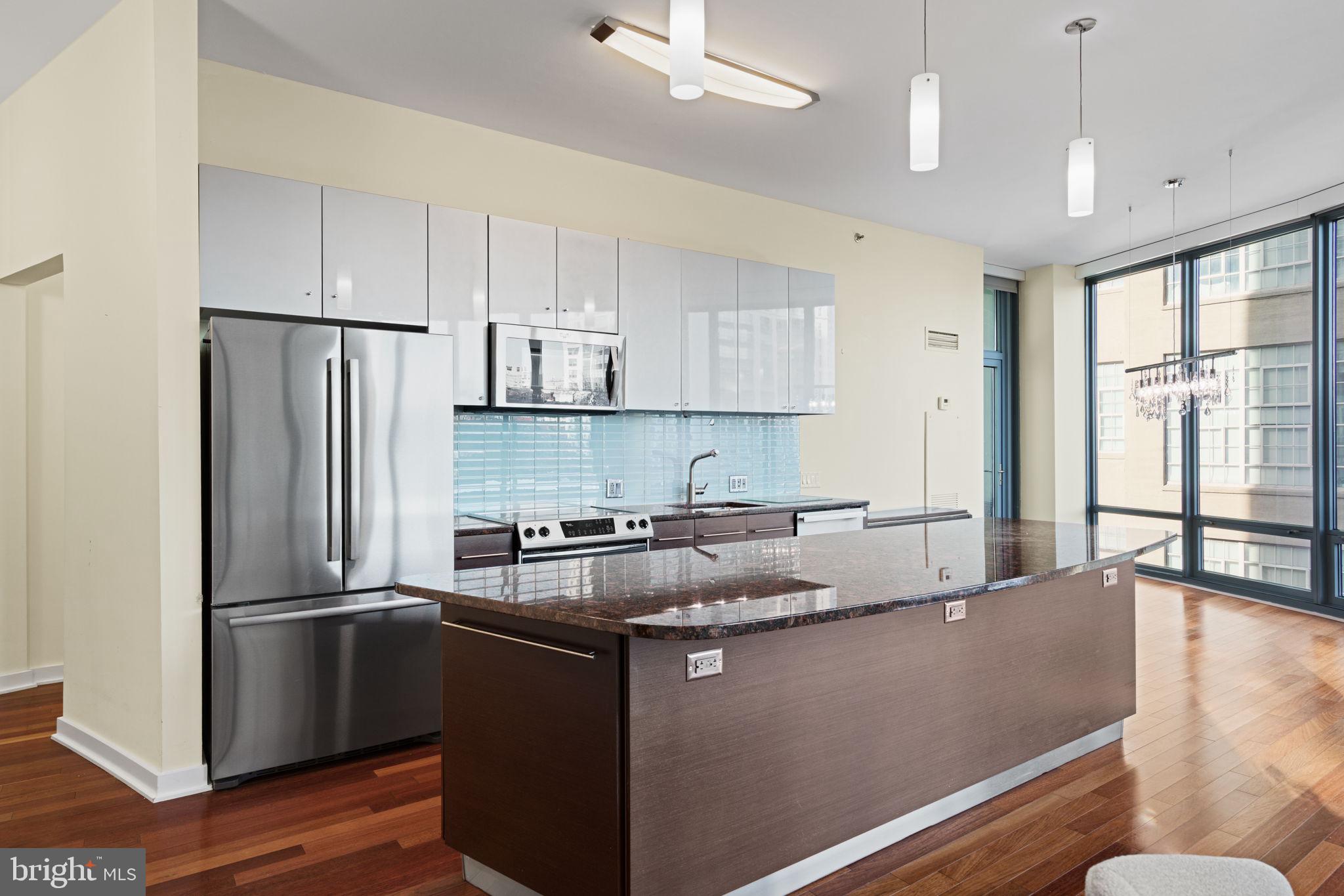 2101 Market Street, Unit 302 Philadelphia, PA 19103 - Photo 14 of 53 a kitchen with stainless steel appliances granite countertop a refrigerator a sink dishwasher a stove and white countertops with wooden floor