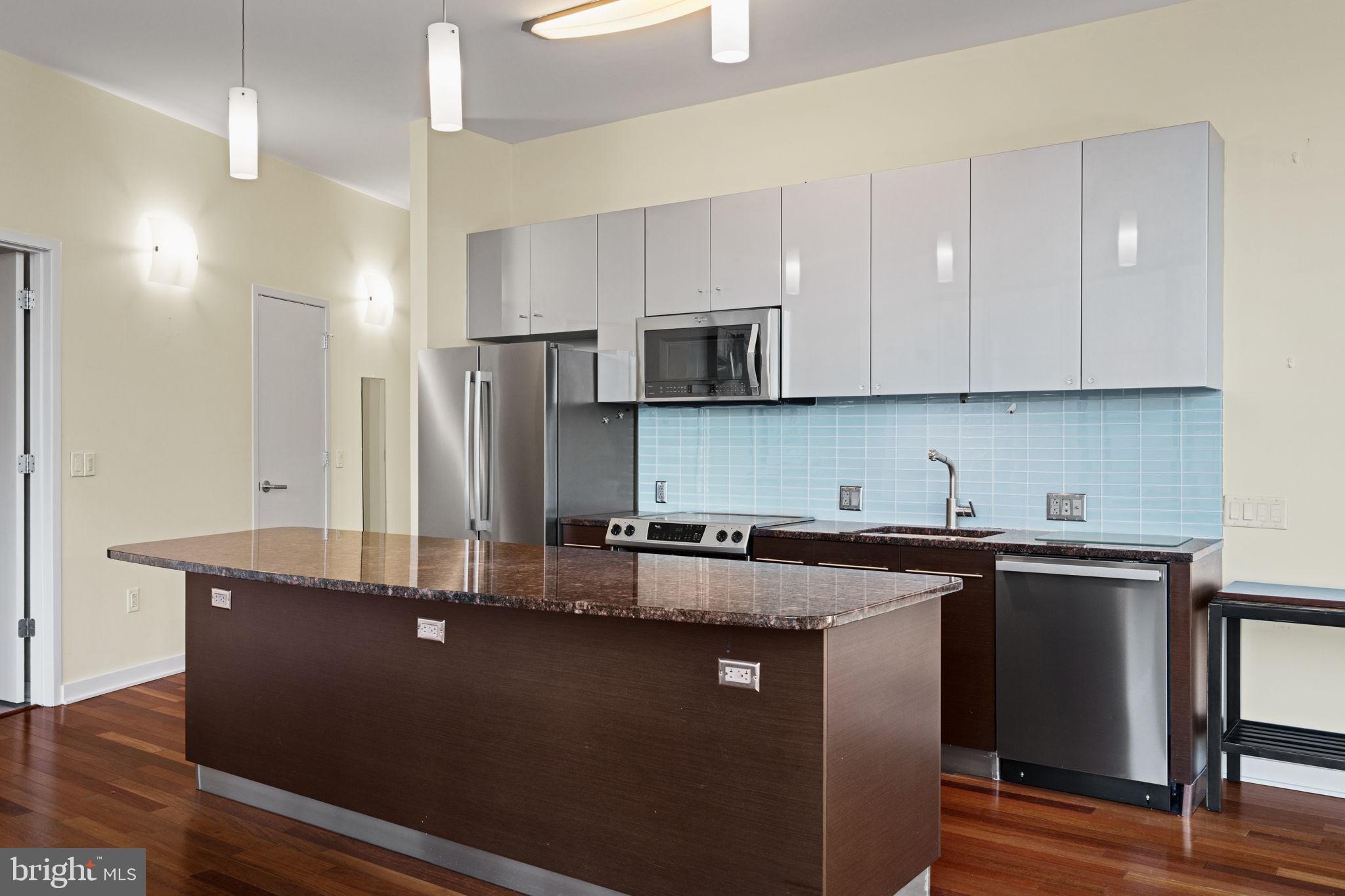 2101 Market Street, Unit 302 Philadelphia, PA 19103 - Photo 15 of 53 a kitchen with kitchen island granite countertop a sink cabinets and stainless steel appliances