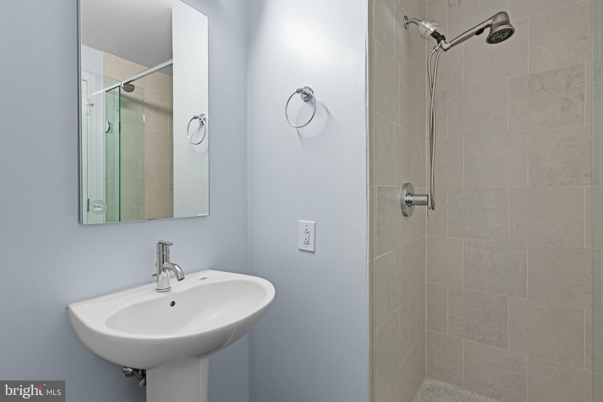 2101 Market Street, Unit 302 Philadelphia, PA 19103 - Photo 16 of 53 a bathroom with a sink a mirror and shower