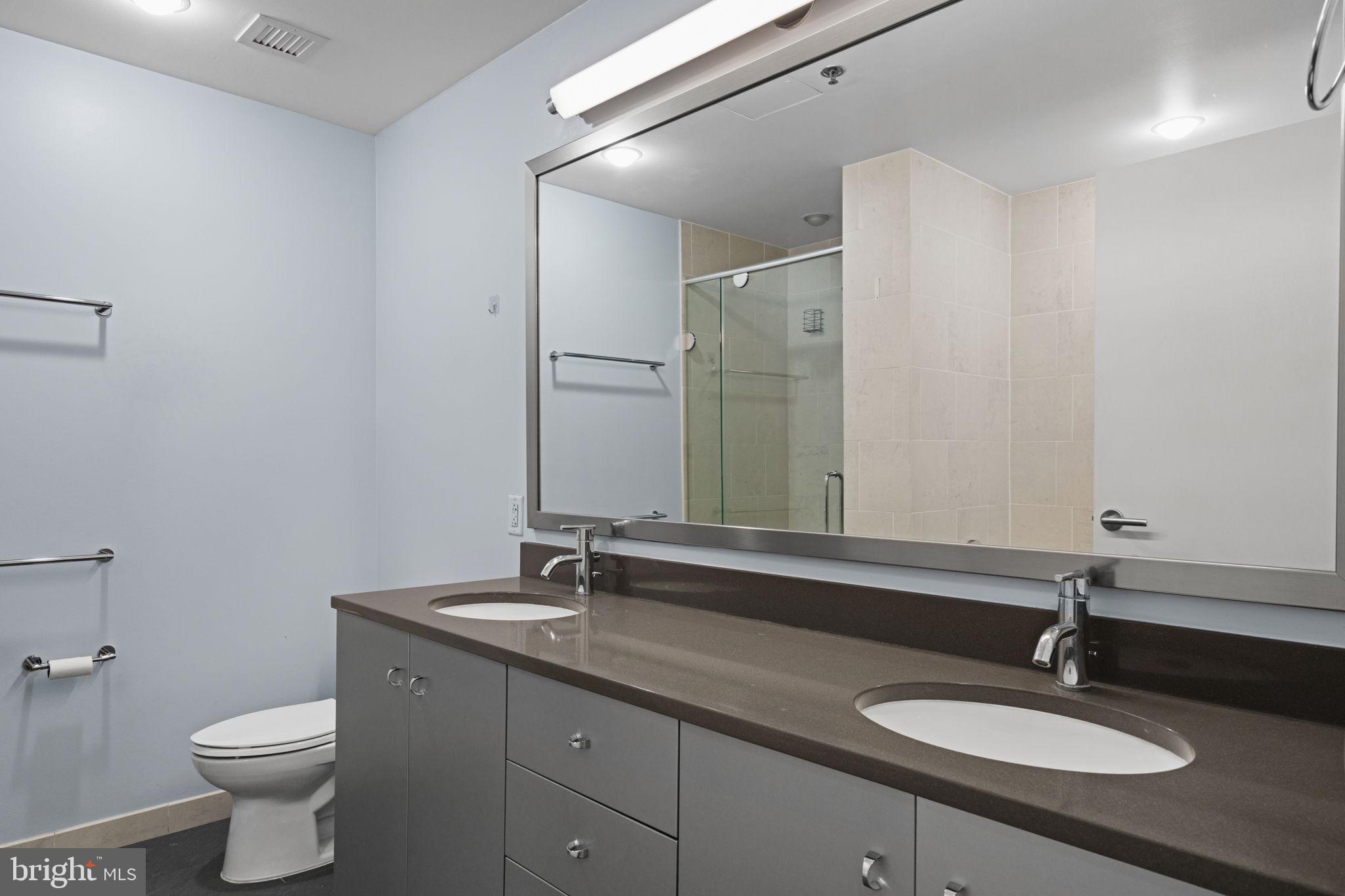 2101 Market Street, Unit 302 Philadelphia, PA 19103 - Photo 30 of 53 a bathroom with a granite countertop sink and a mirror