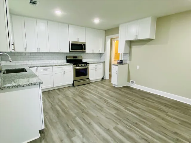 a kitchen with granite countertop white cabinets and stainless steel appliances