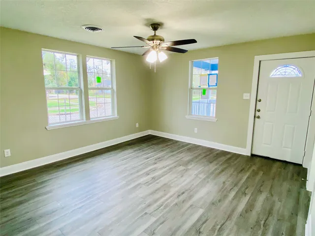 a view of an empty room with wooden floor and a window