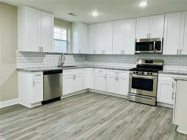 a kitchen with stainless steel appliances granite countertop a stove a sink and a microwave