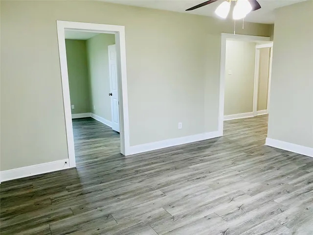 an empty room with wooden floor and a chandelier fan