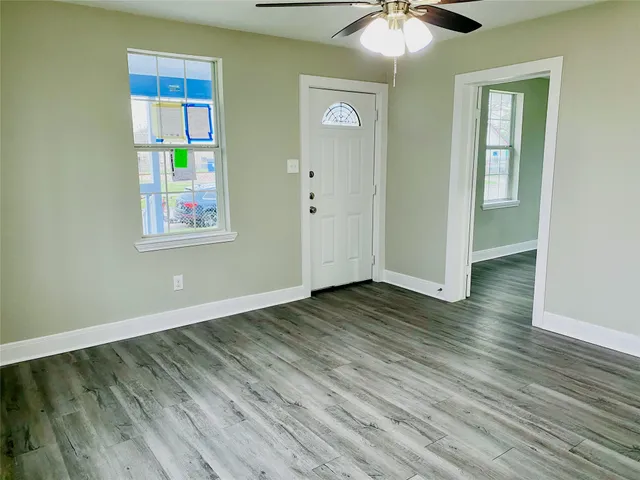 an empty room with wooden floor fan and windows