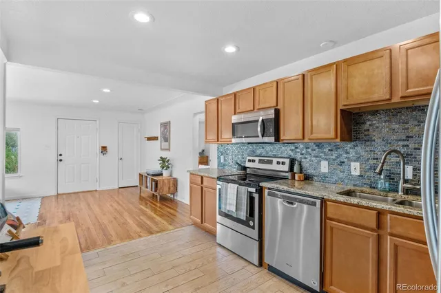 a kitchen with stainless steel appliances granite countertop a stove a sink dishwasher and a microwave oven with wooden floor