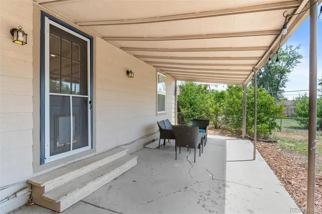 a view of a patio with table and chairs and floor to ceiling window