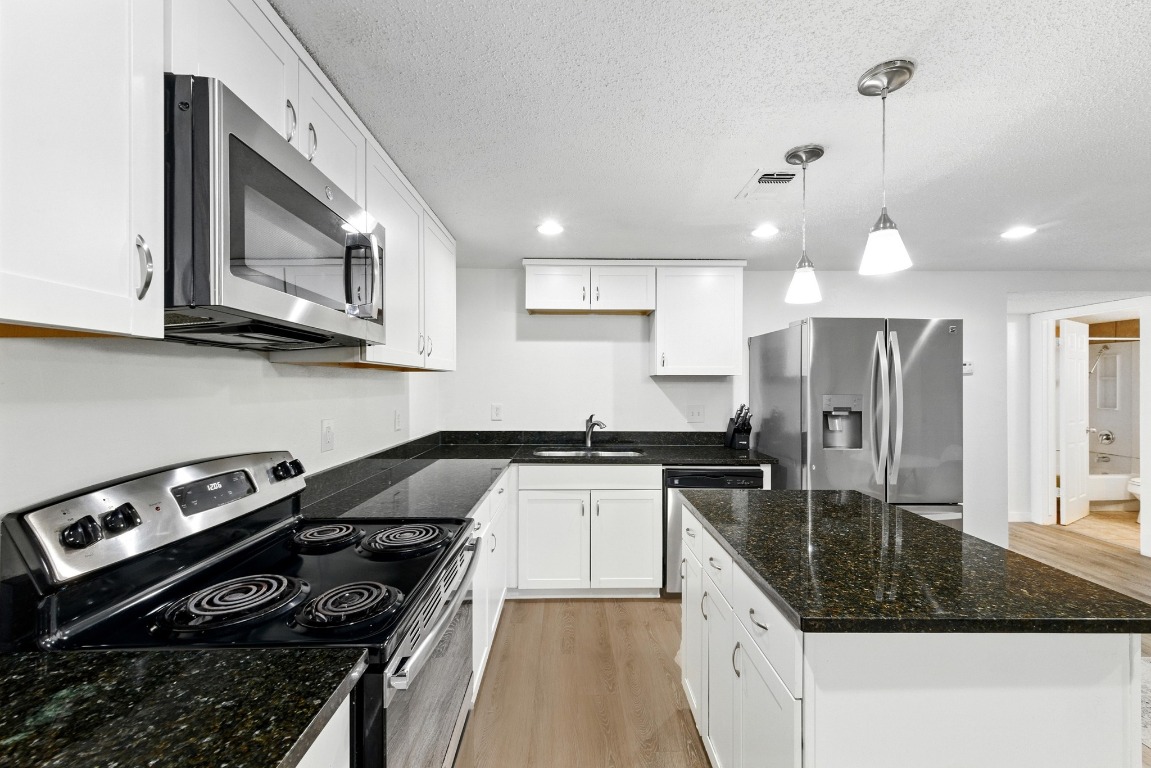 2401 Leon Street, Unit 306 Austin, TX 78705 - Photo 12 of 27 a kitchen with stainless steel appliances granite countertop a stove a sink and a microwave