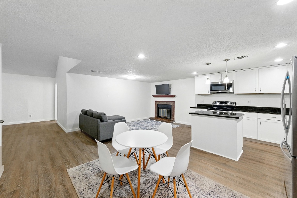 2401 Leon Street, Unit 306 Austin, TX 78705 - Photo 13 of 27 a kitchen with stainless steel appliances granite countertop a stove a sink a microwave a dining table and chairs with wooden floor