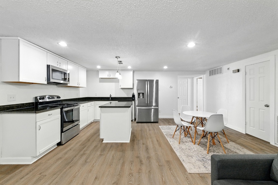 2401 Leon Street, Unit 306 Austin, TX 78705 - Photo 3 of 27 a kitchen with stainless steel appliances kitchen island granite countertop a stove a sink a refrigerator and white cabinets with wooden floor