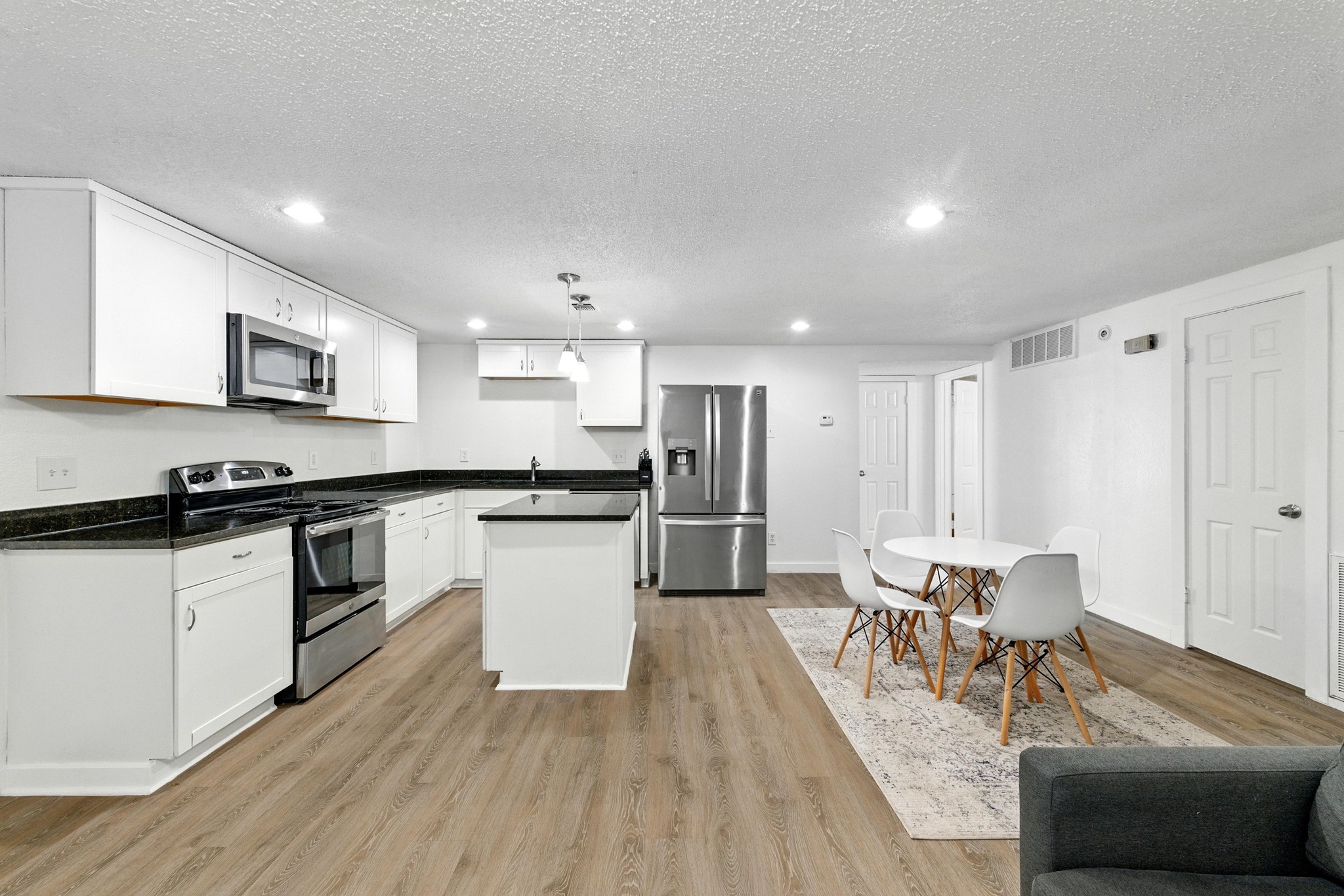 2401 Leon Street, Unit 306 Austin, TX 78705 - Photo 6 of 27 a kitchen with stainless steel appliances kitchen island granite countertop a stove a sink a refrigerator and white cabinets with wooden floor