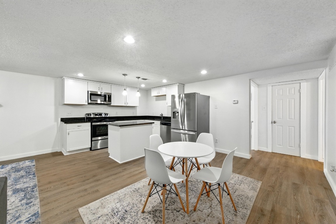 2401 Leon Street, Unit 306 Austin, TX 78705 - Photo 7 of 27 a kitchen with a table chairs refrigerator and microwave