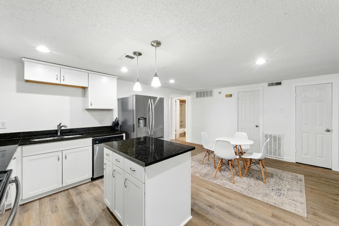 2401 Leon Street, Unit 306 Austin, TX 78705 - Photo 8 of 27 a kitchen with granite countertop a sink and white cabinets with wooden floor
