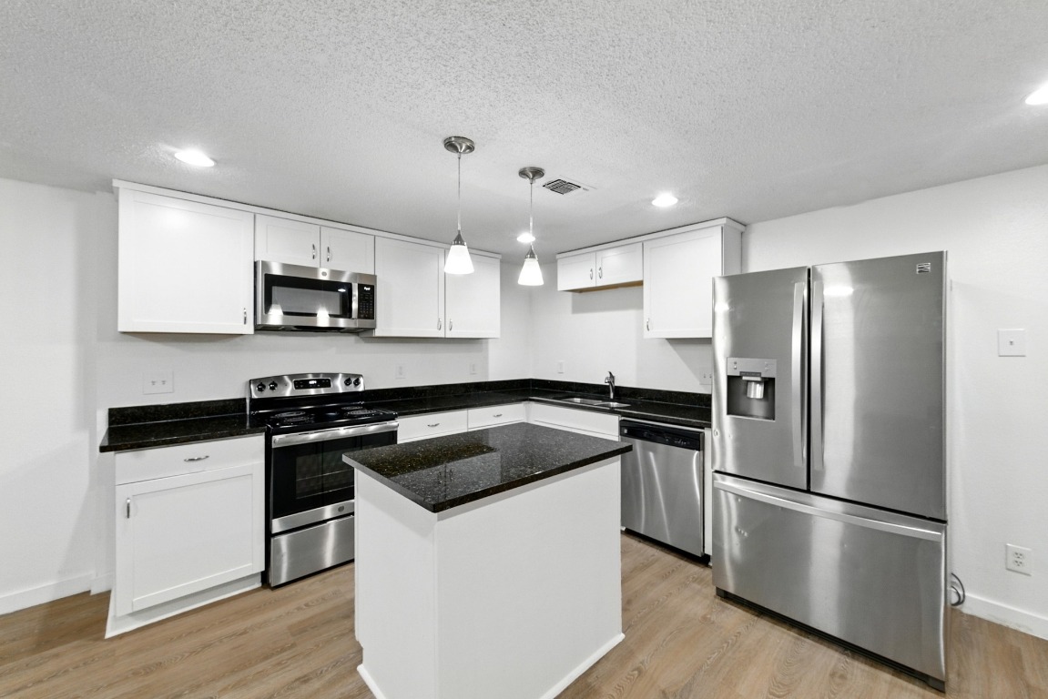 2401 Leon Street, Unit 306 Austin, TX 78705 - Photo 9 of 27 a kitchen with kitchen island a white cabinets and stainless steel appliances