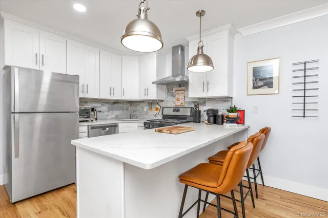 a kitchen with stainless steel appliances granite countertop a stove a sink a dining table and chairs with wooden floor