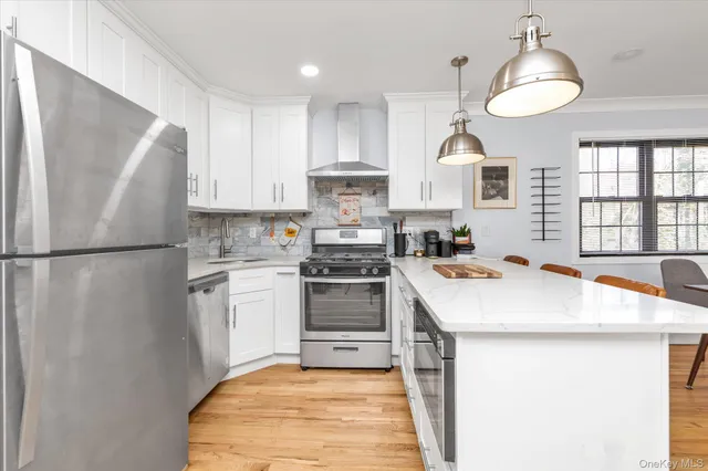 a kitchen with stainless steel appliances a refrigerator a sink a stove a dining table and chairs