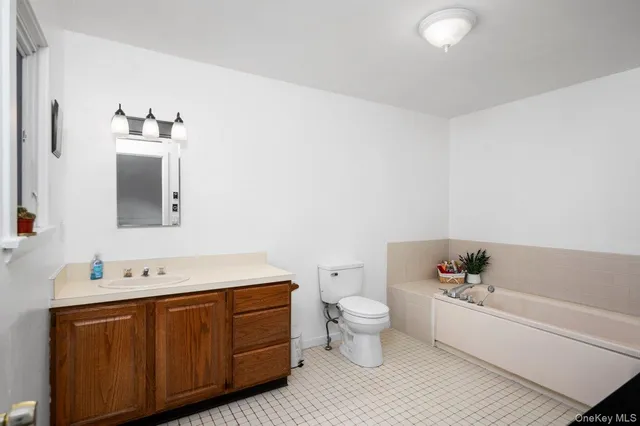 a spacious bathroom with a bathtub sink mirror and toilet